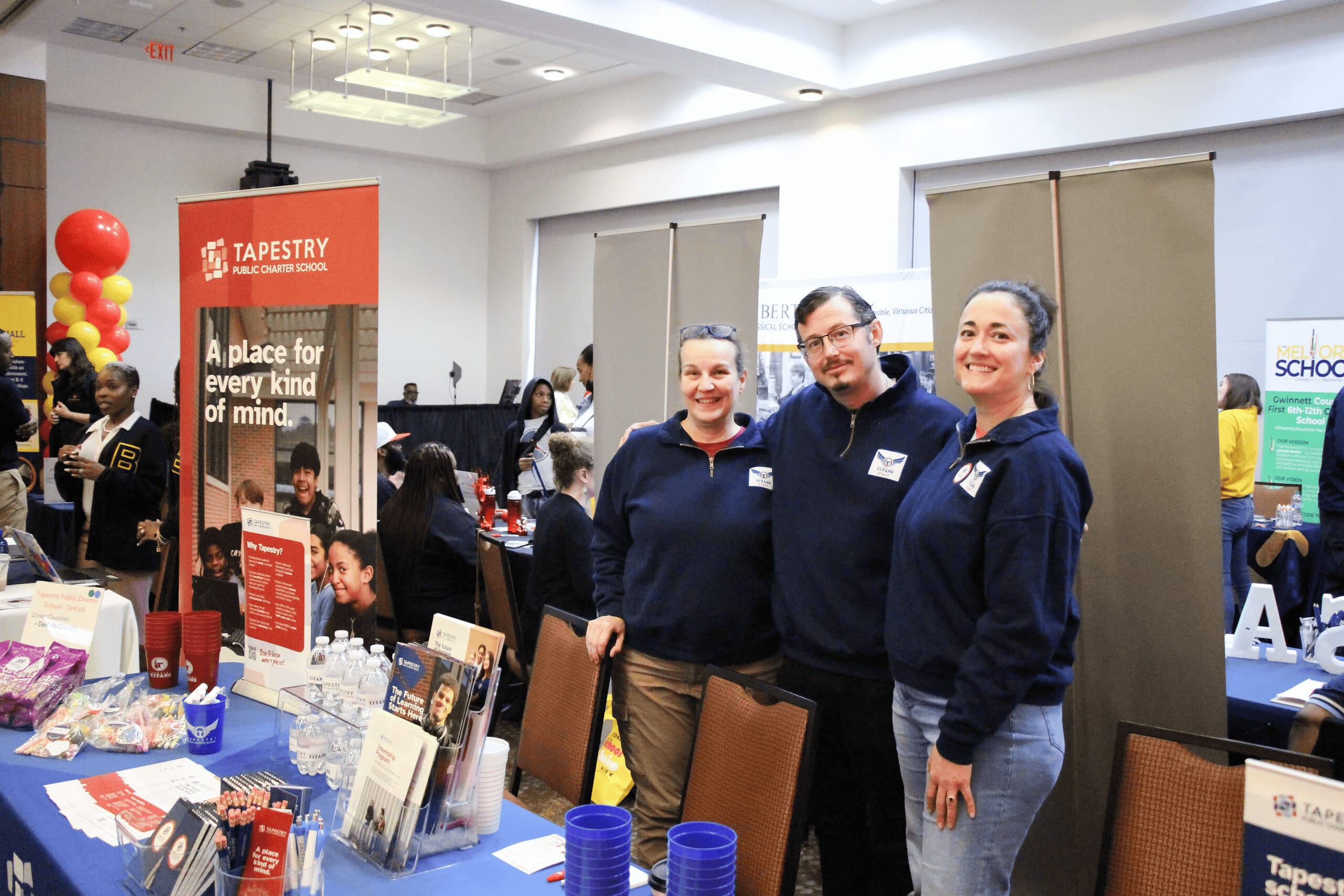 Three staff members at Tapestry Public Charter School education fair booth