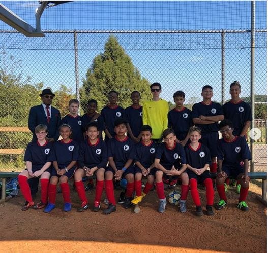 Youth soccer team posing in navy uniforms with red socks